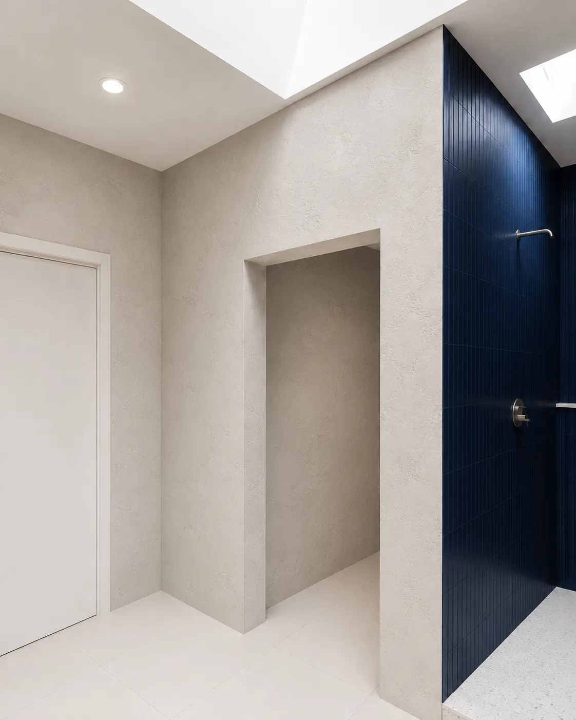 A light gray Venetian Marmorino bathroom wall beside a navy fluted-tile shower and a wood vanity, in a Santa Ana project.